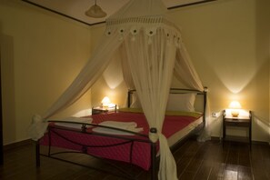 A single bed with a canopy, bedside tables with lamps, and a tiled floor.