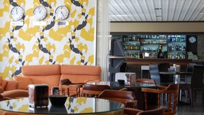 A bar area with a bar counter, shelves of bottles, and a clock.