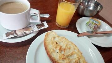 Un desayuno con una taza de café, un vaso de zumo de naranja, una porción de mantequilla, un cuchillo y una tostada en un plato.