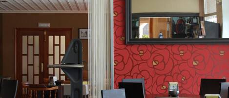 A restaurant interior with a traditional Japanese-style entrance, a red patterned wall, and a large mirror.