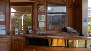 A reception desk with wooden paneling, a clock, and framed certificates.