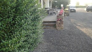 Een gebouw met een betegeld terras, buiten zitplaatsen en een grindpad.