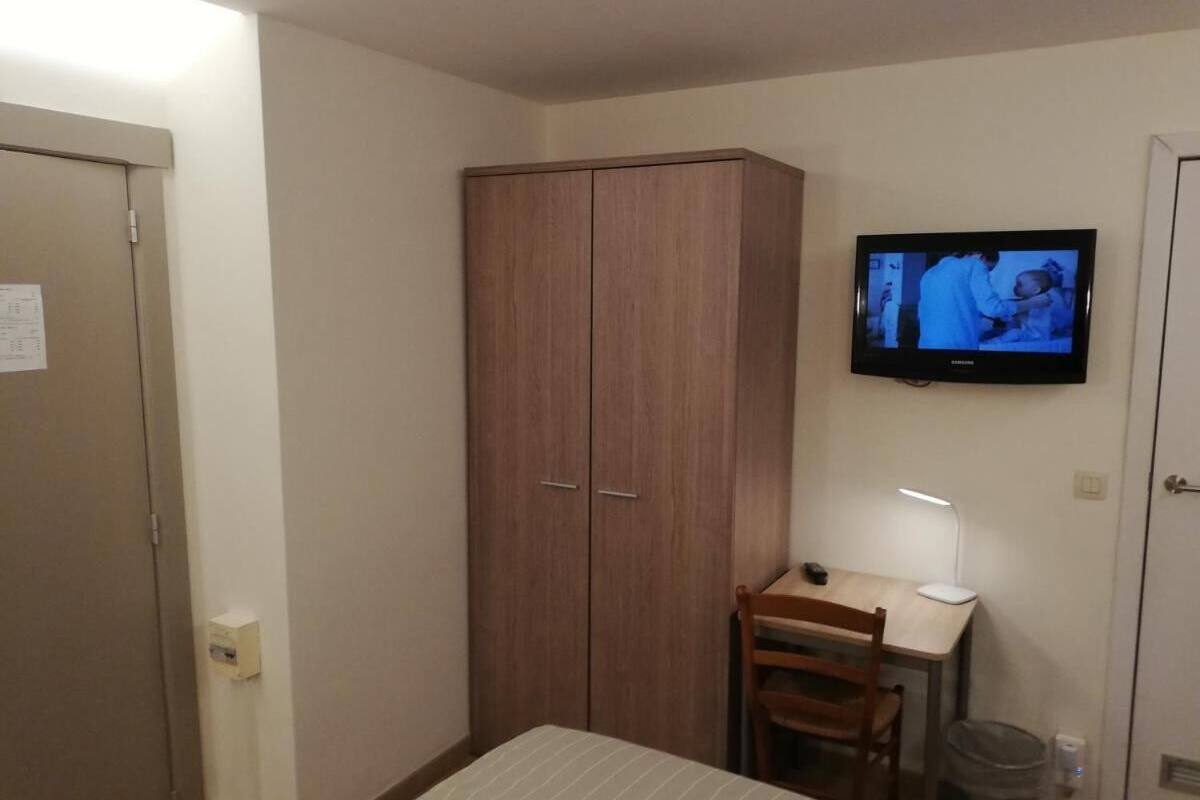 Ein Schlafzimmer mit einem Bett, einem Schreibtisch mit Stuhl, einem Fernseher und einem Kleiderschrank.