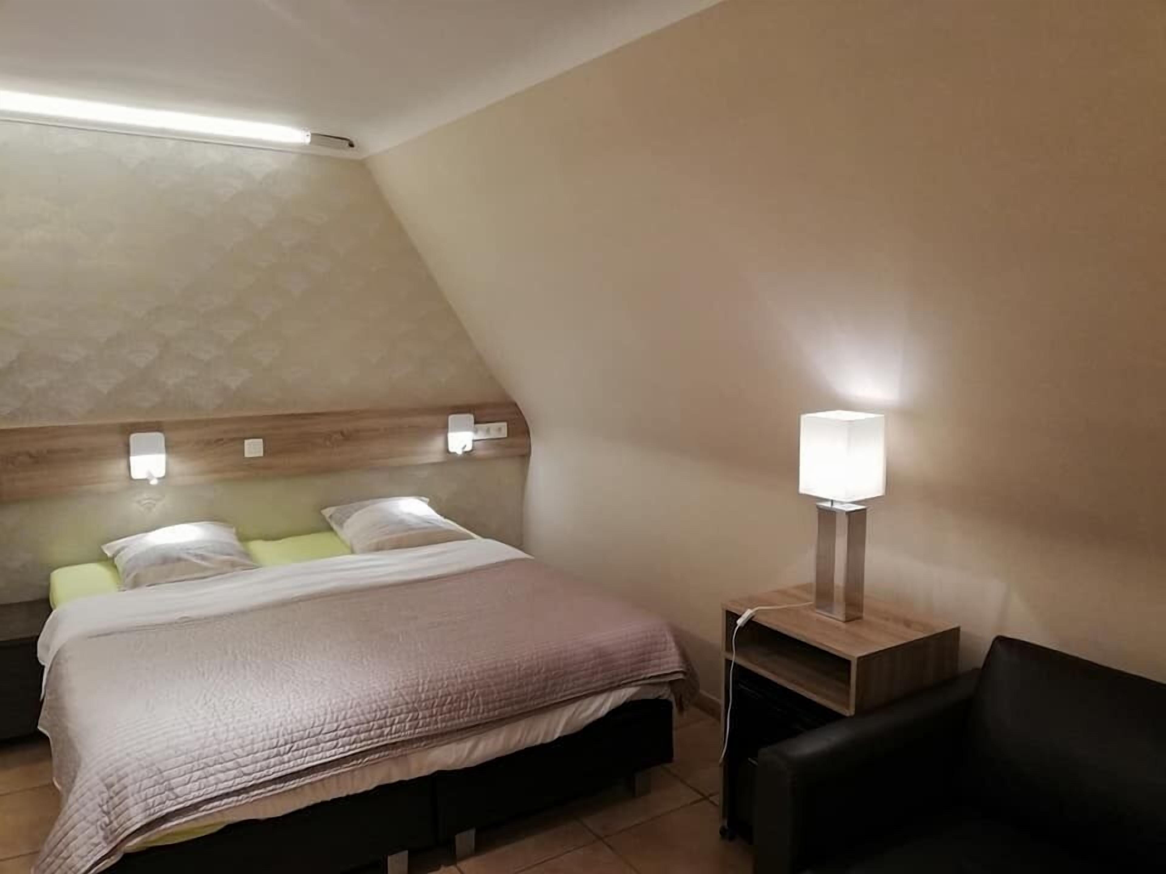 Une chambre d’hôtel comprenant un lit, des tables de chevet, une lampe et un petit coin salon.