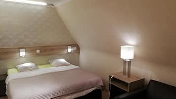 Une chambre d’hôtel comprenant un lit, des tables de chevet, une lampe et un petit coin salon.