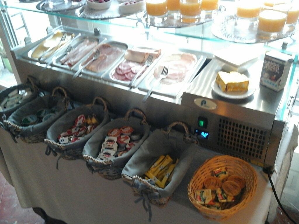 A buffet with various food items and baskets of bread.