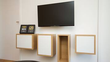 Une chambre moderne équipée d’un téléviseur à écran plat fixé au mur, de meubles en bois fixés au mur et d’un symbole Wi-Fi encadré.