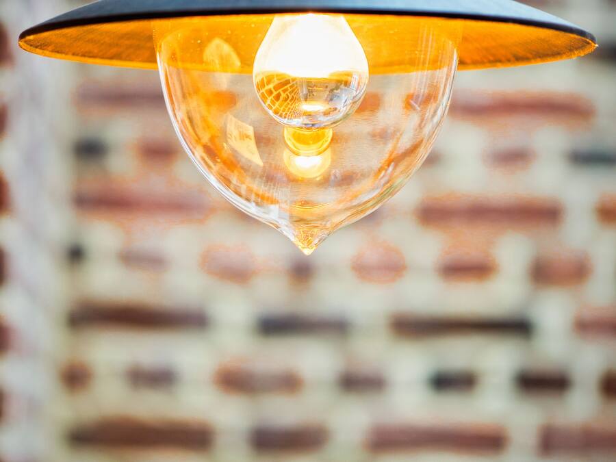 Een hanglamp met een glazen behuizing en zichtbare gloeilamp.