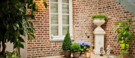 A brick building with a window, potted plants, and a statue.