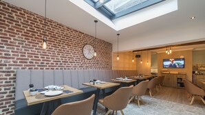 Moderni ravintola, jossa on tiiliseinät, puupöydät ja mukavat istuimet.