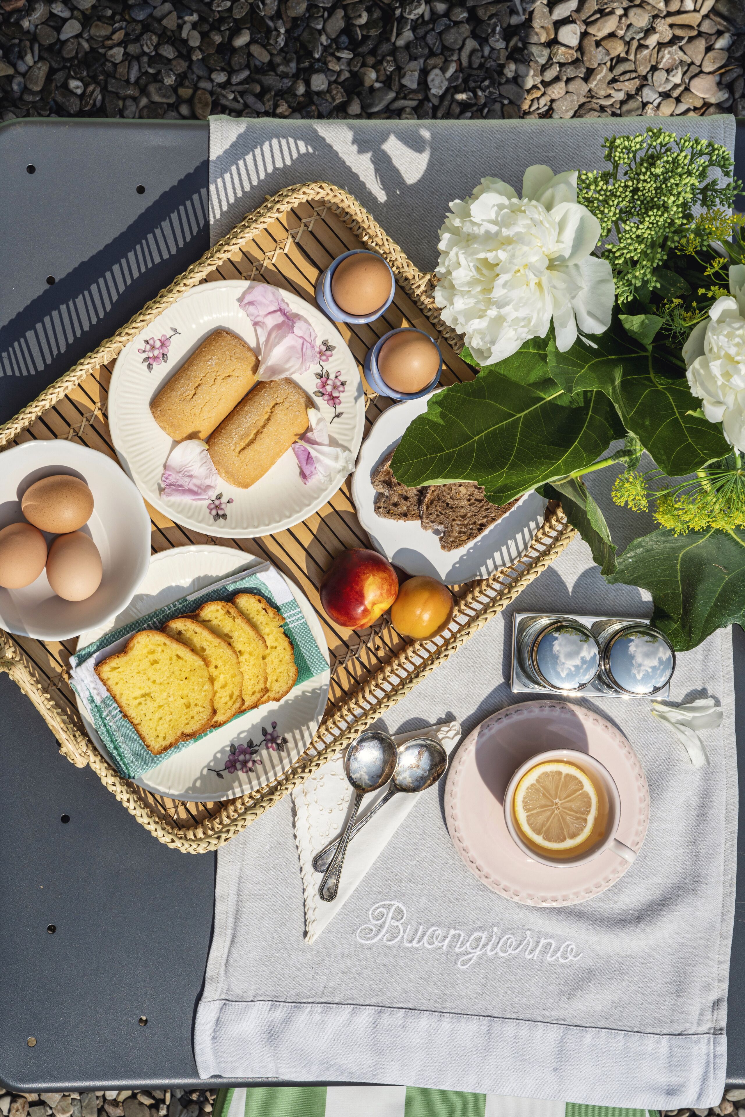 Un'apparecchiatura da picnic con pane, uova e fiori su una tovaglia.