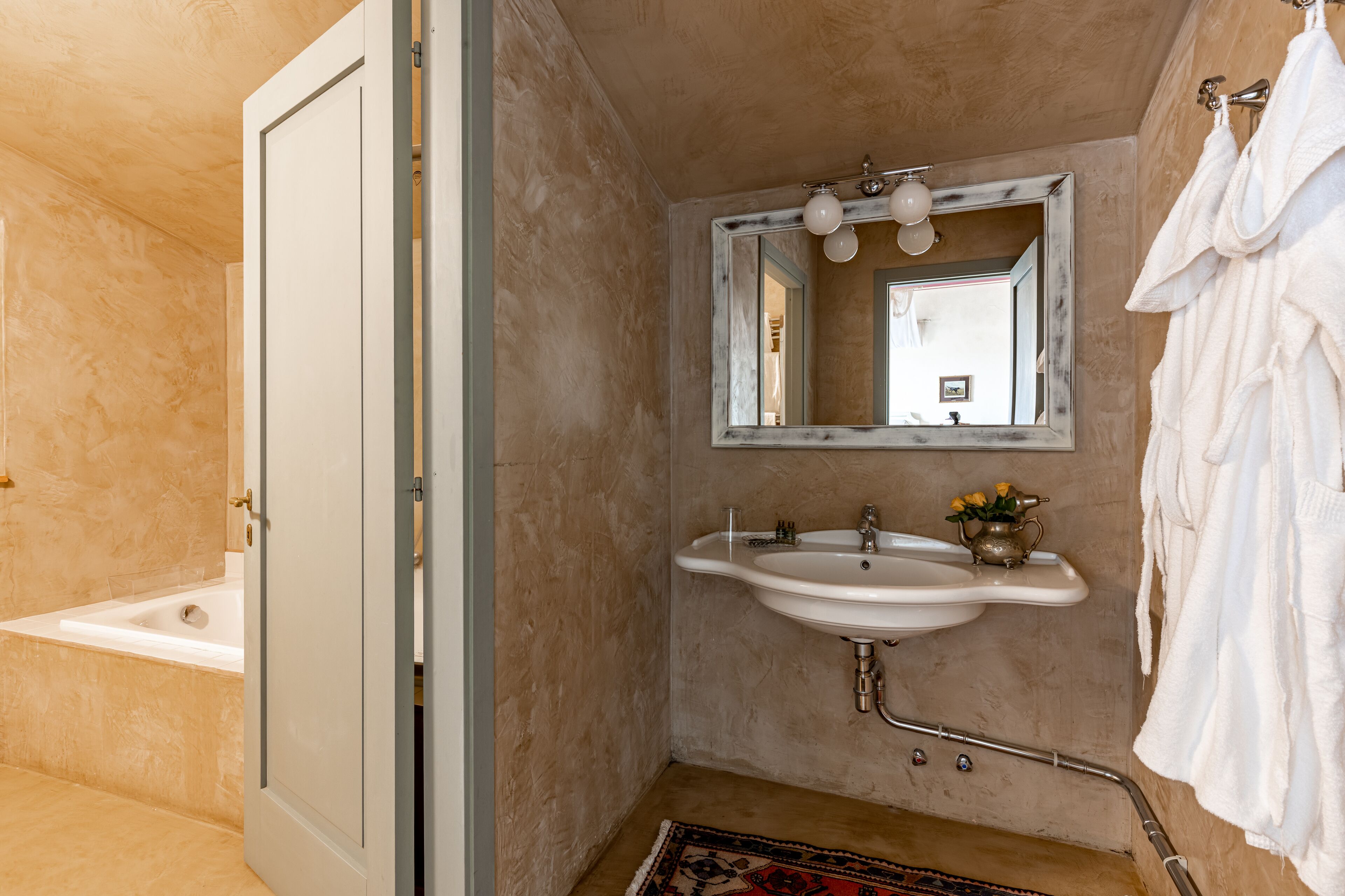 A bathroom with a bathtub, a sink with a mirror above it, and a towel rack.