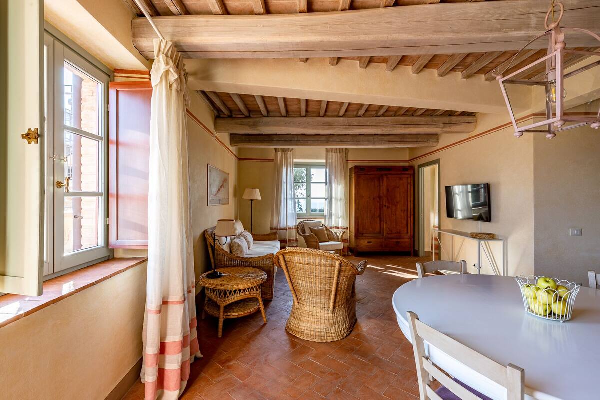 A cozy room with a bed, wicker furniture, a dining table, and a TV.