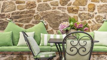 A stone wall with a green sofa and a chair with a metal frame.