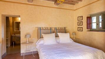 A bedroom with a bed, bedside tables, a mirror, and a window with curtains.
