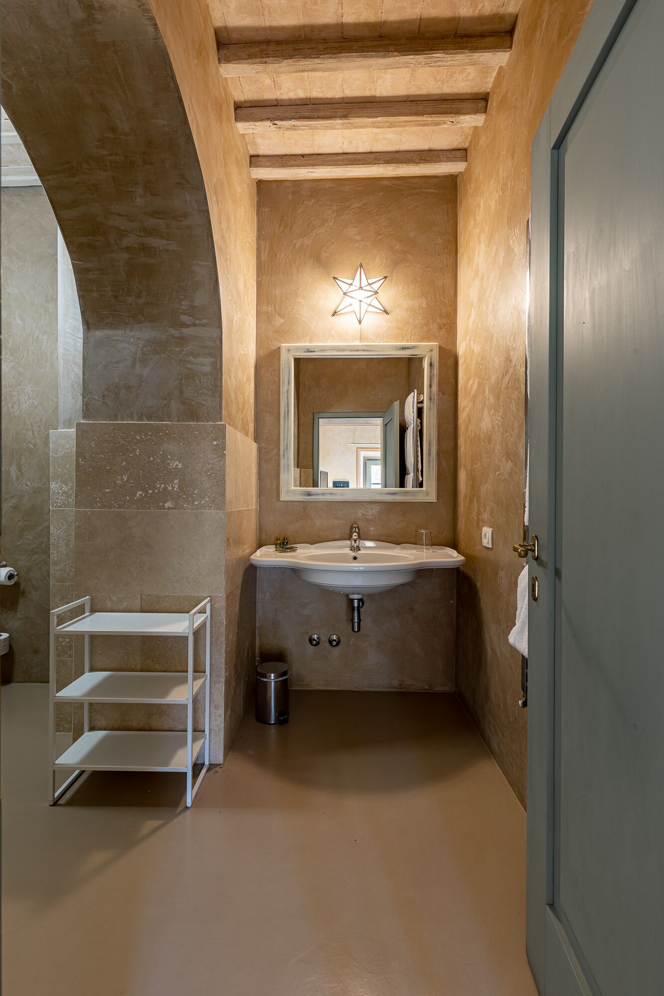 A bathroom with a white sink, a star-shaped light fixture above the mirror, and a white shelf unit.