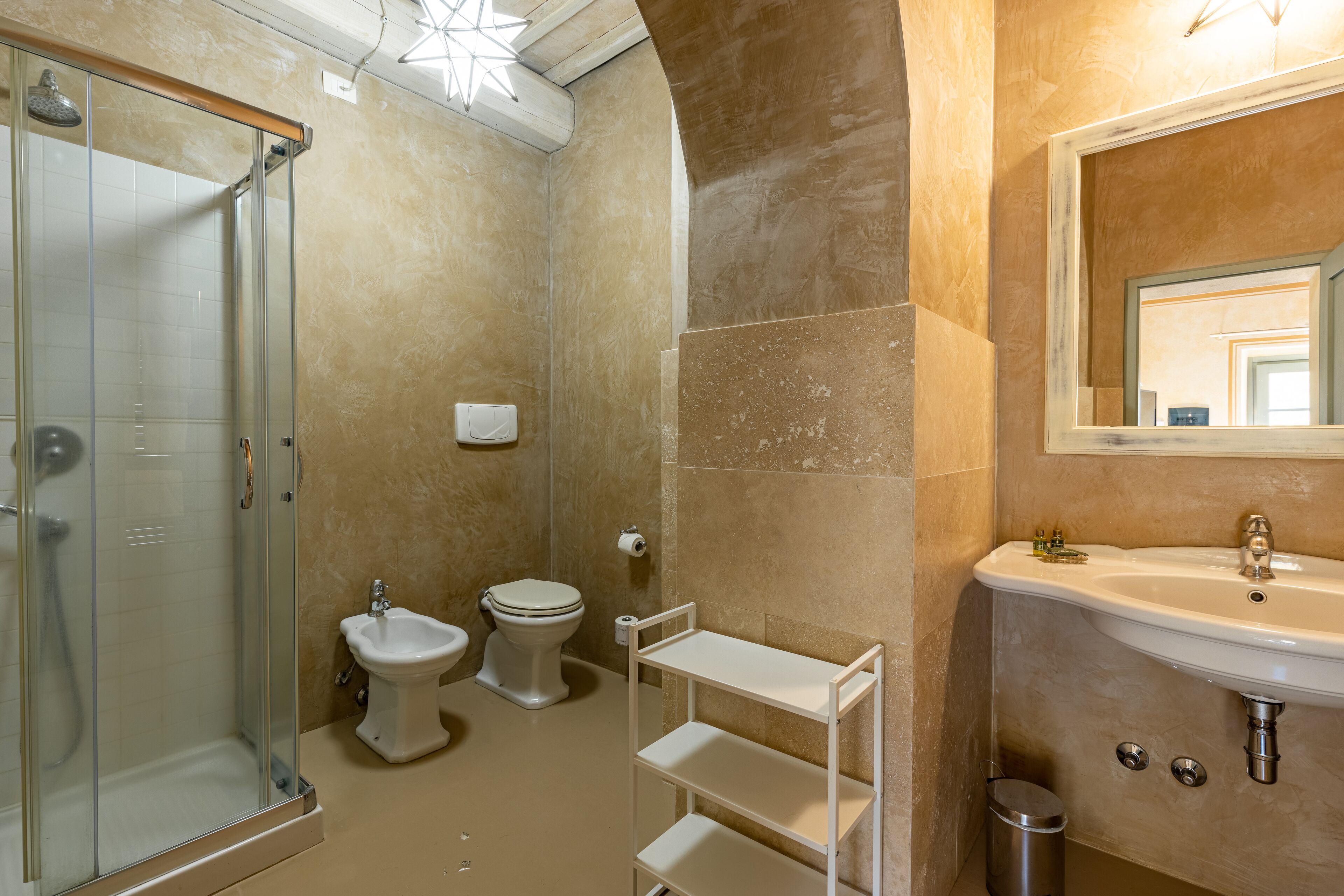 Une salle de bain avec une douche à parois de verre, des toilettes, un bidet et un lavabo avec un miroir.