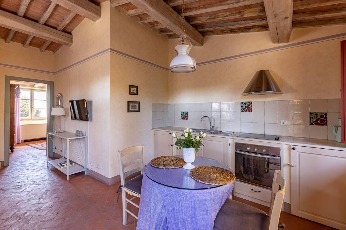 A kitchen with a wooden ceiling, white cabinets, a stove, and a sink.
