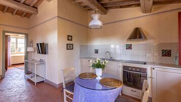 Una cocina con techo de madera, armarios blancos, estufa y lavaplatos.
