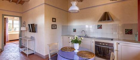 A kitchen with a wooden ceiling, white cabinets, a stove, and a sink.