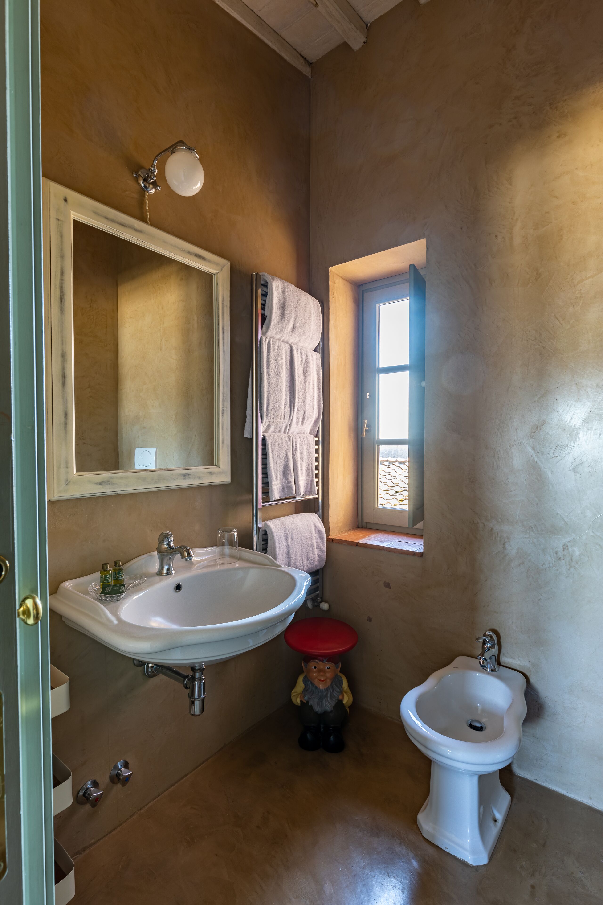 Un baño con un lavamanos grande, un bidé, un espejo y una ventana.