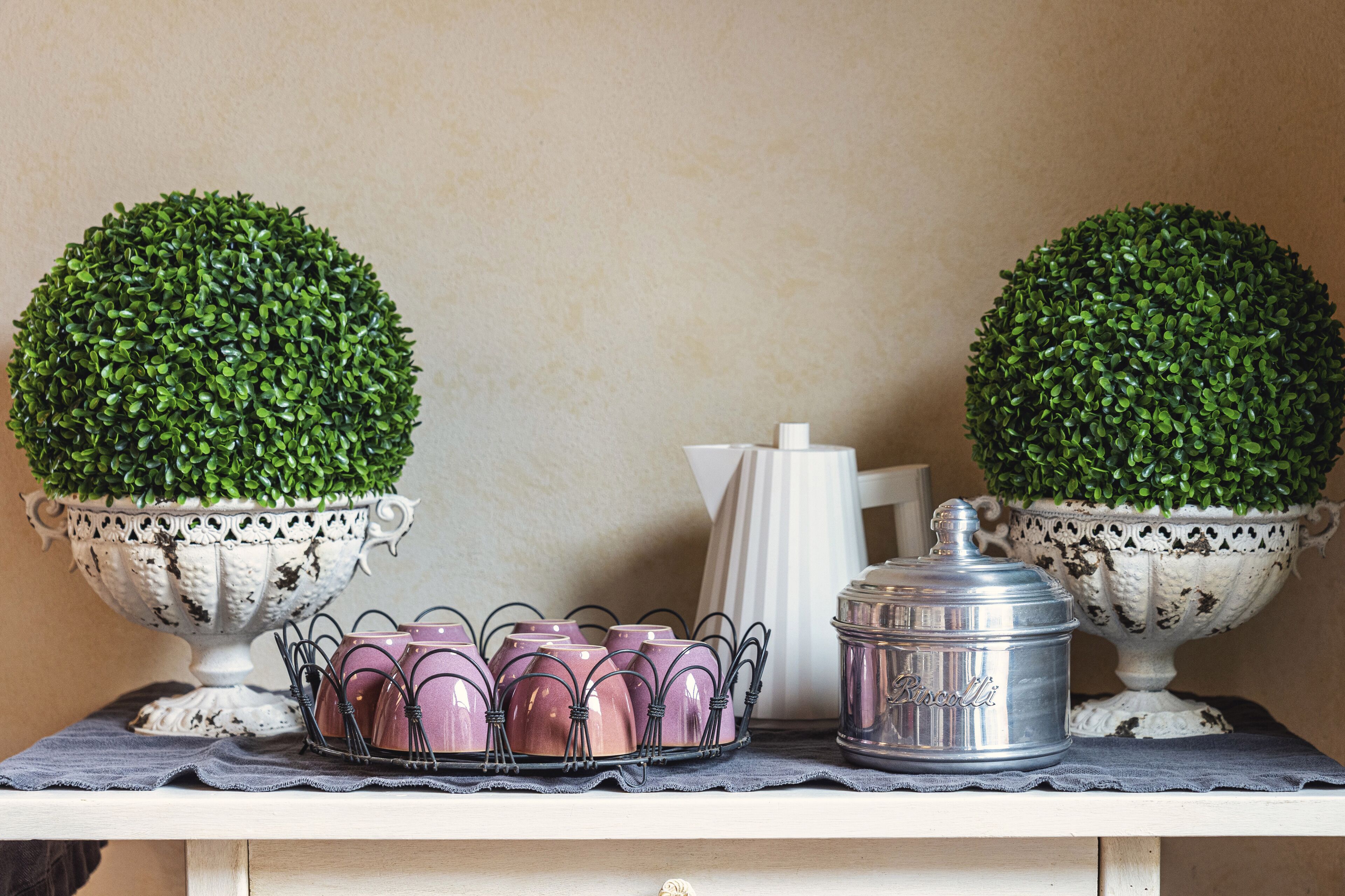 A table with two ornate vases, a metal container, and a tray of pink cups.