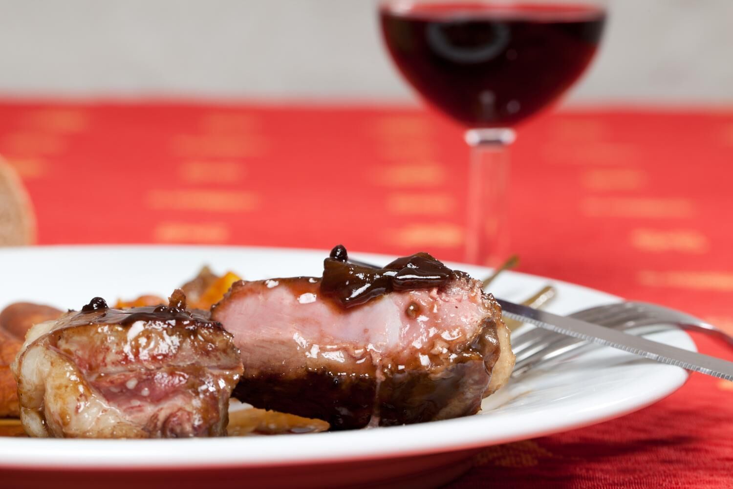Un plato con carne en rodajas y una copa de vino tinto.
