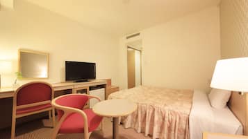 Una habitación de hotel con cama, escritorio, silla, televisor y una mesita.