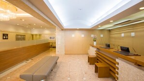 Eine moderne Hotelhalle mit einer langen Rezeption, einer Bank und einem Oberlicht.