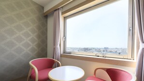 Ein Hotelzimmer mit großem Fenster, zwei Stühlen und einem kleinen Tisch.