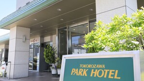 Das äußere Erscheinungsbild des Tokorozawa Park Hotels mit freiem Eingang, Pflanzgefäßen und einem Schild.