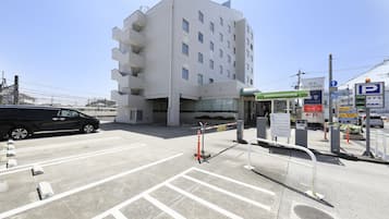 A parking lot with a modern building in the background, a gas station, and a hotel sign.