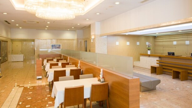 Eine moderne Hotelhalle mit einer langen Rezeption, mehreren Sitzbereichen und einer großen Kronleuchter.