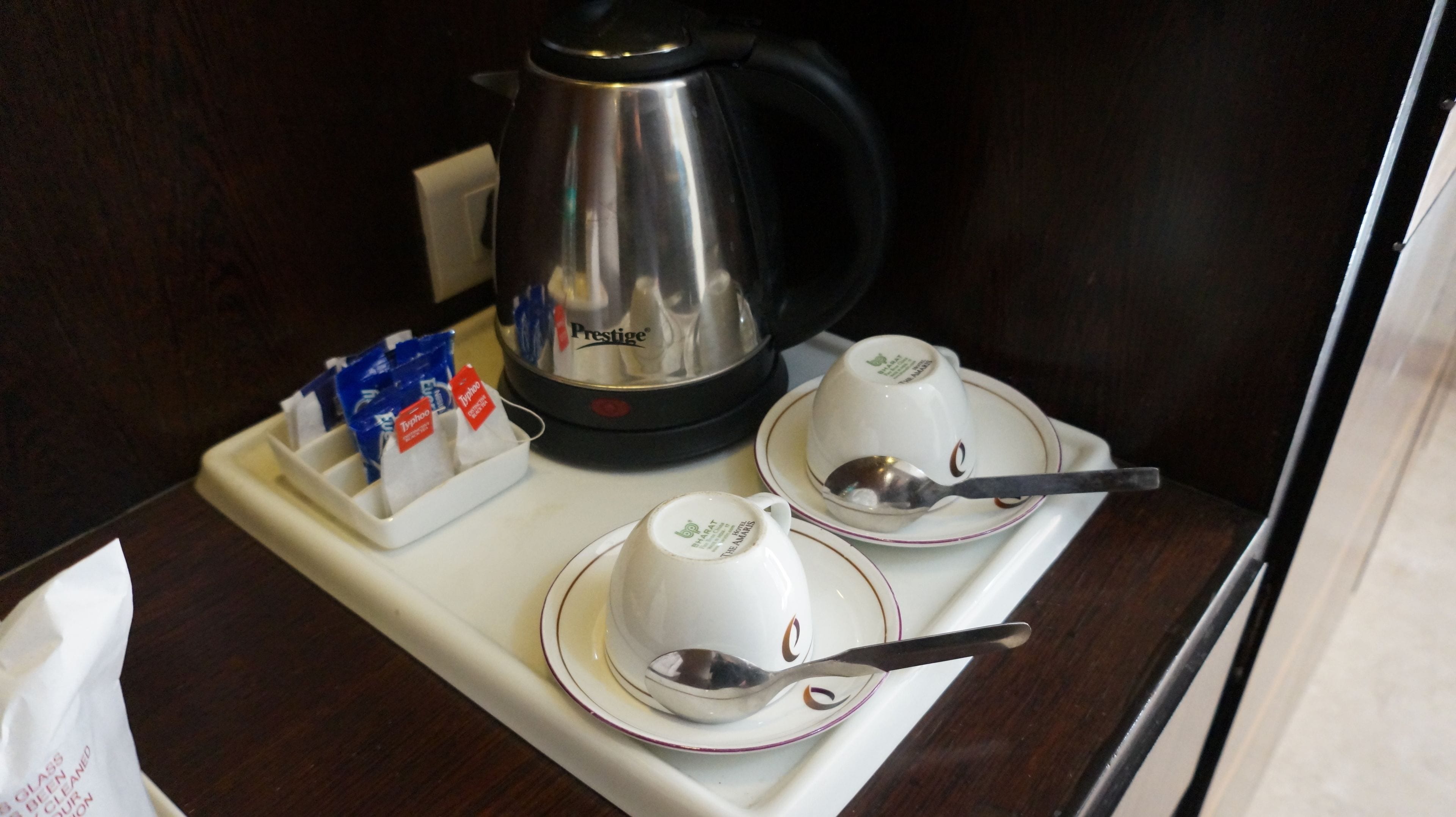 A breakfast tray with two cups, two spoons, and a coffee pot.