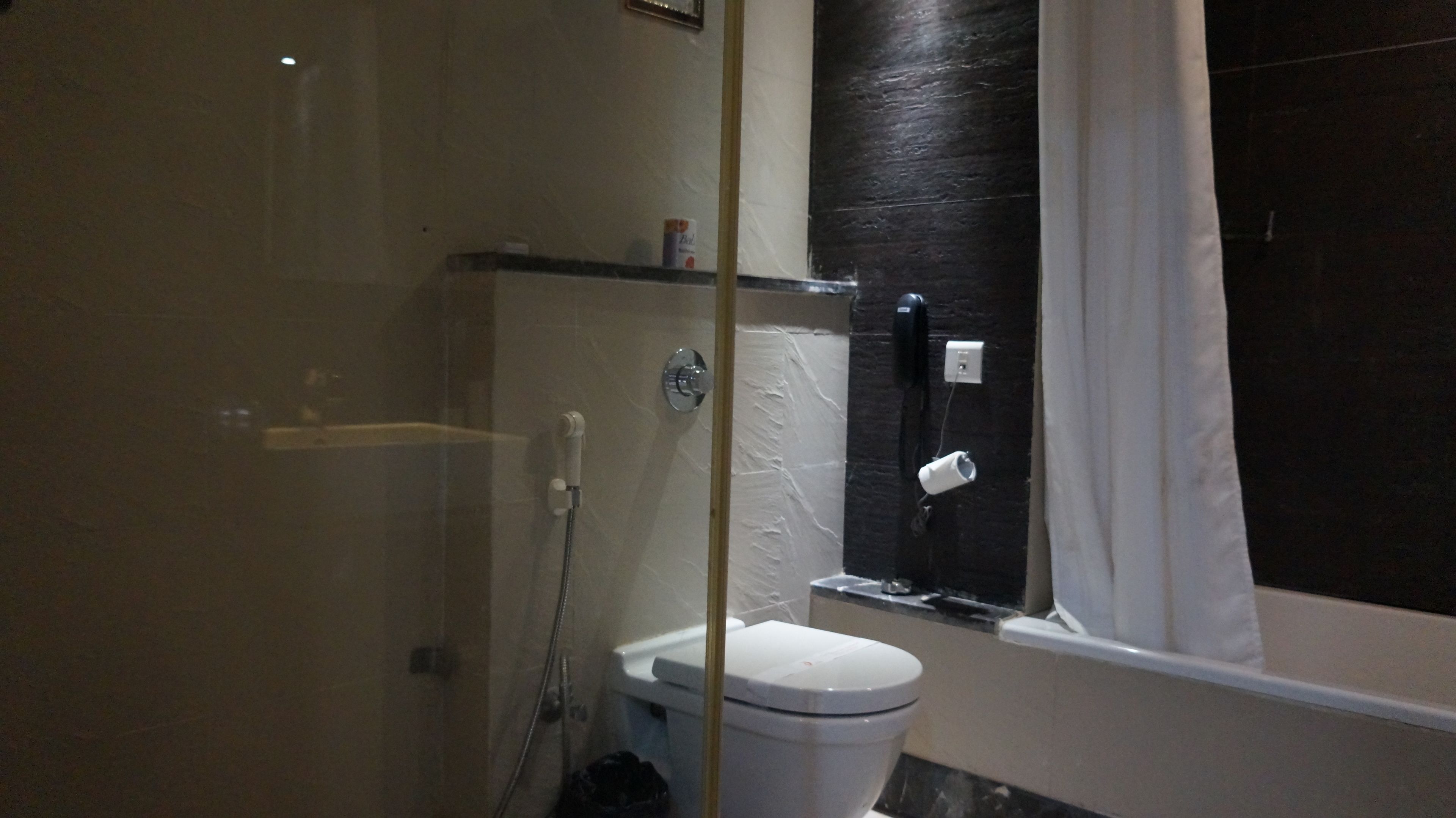 Et badeværelse med toilet, bruser og badekar.