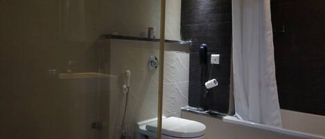 Et badeværelse med toilet, bruser og badekar.