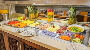 A buffet with various food items including fruits, vegetables, and meats.