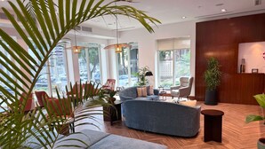 A modern hotel lobby with a large seating area, large windows, and indoor plants. - Hilton Garden Inn Panama City Downtown, Panama (Panama City)