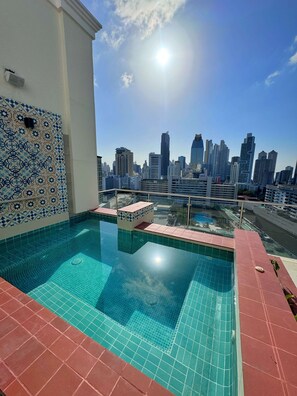 A rooftop pool with a city skyline view, tiled walls, and a clear sky. - Hilton Garden Inn Panama City Downtown, Panama (Panama City)
