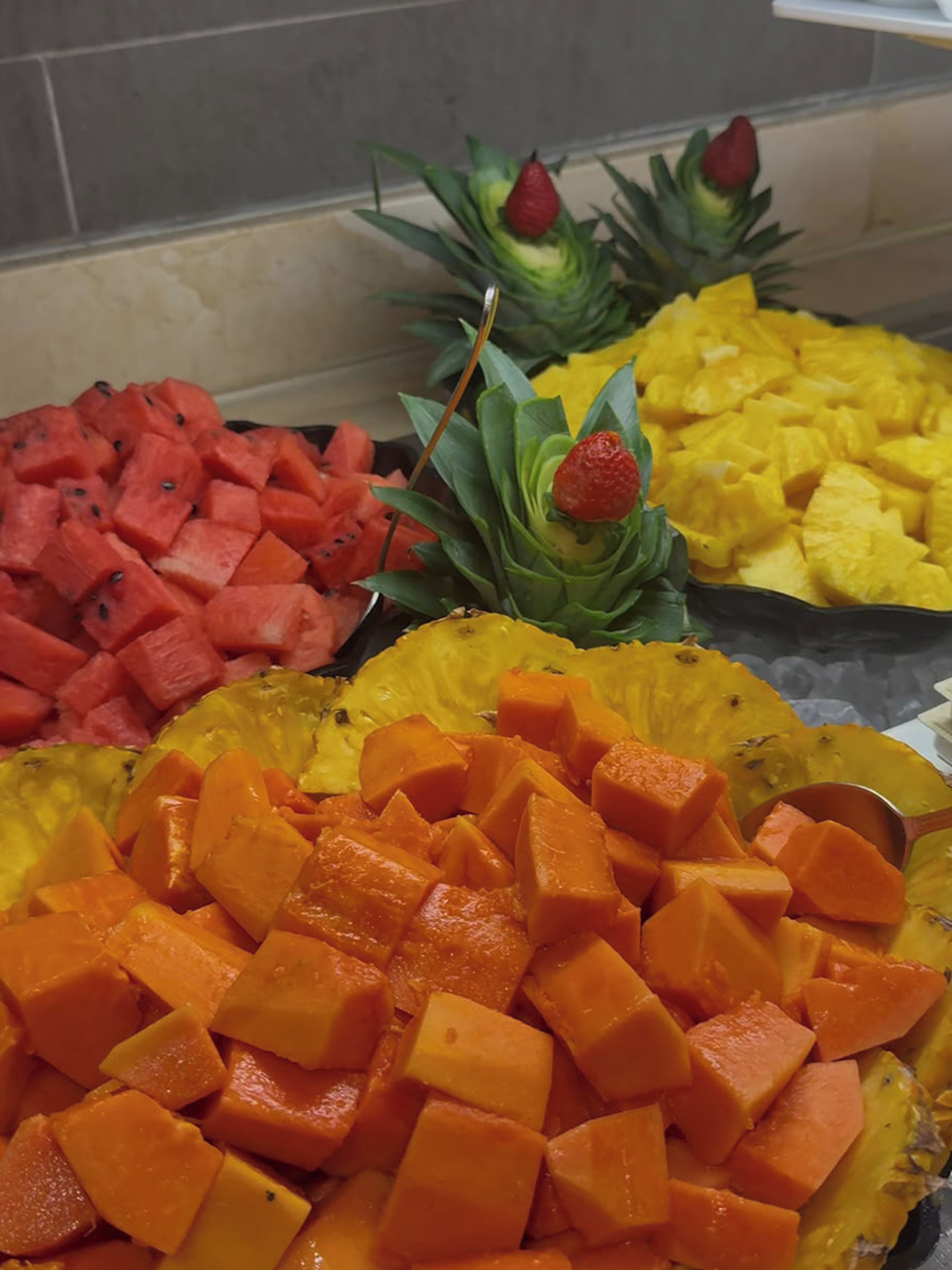 A buffet with various fruits including watermelon, pineapple, and mango.