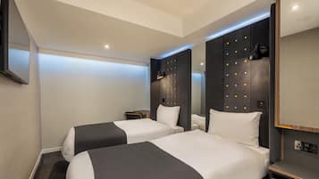 Une chambre d’hôtel avec deux lits, un téléviseur à écran plat, une lampe fixée au mur et un panneau de commande.