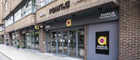 Een hotel met een moderne gevel, grote ramen en een opvallend logo.