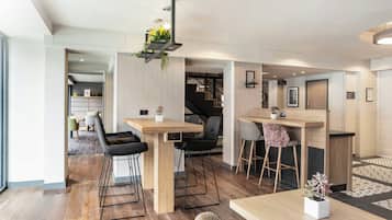 Un intérieur moderne comprenant un coin repas, des tabourets de bar et un escalier menant à une mezzanine.