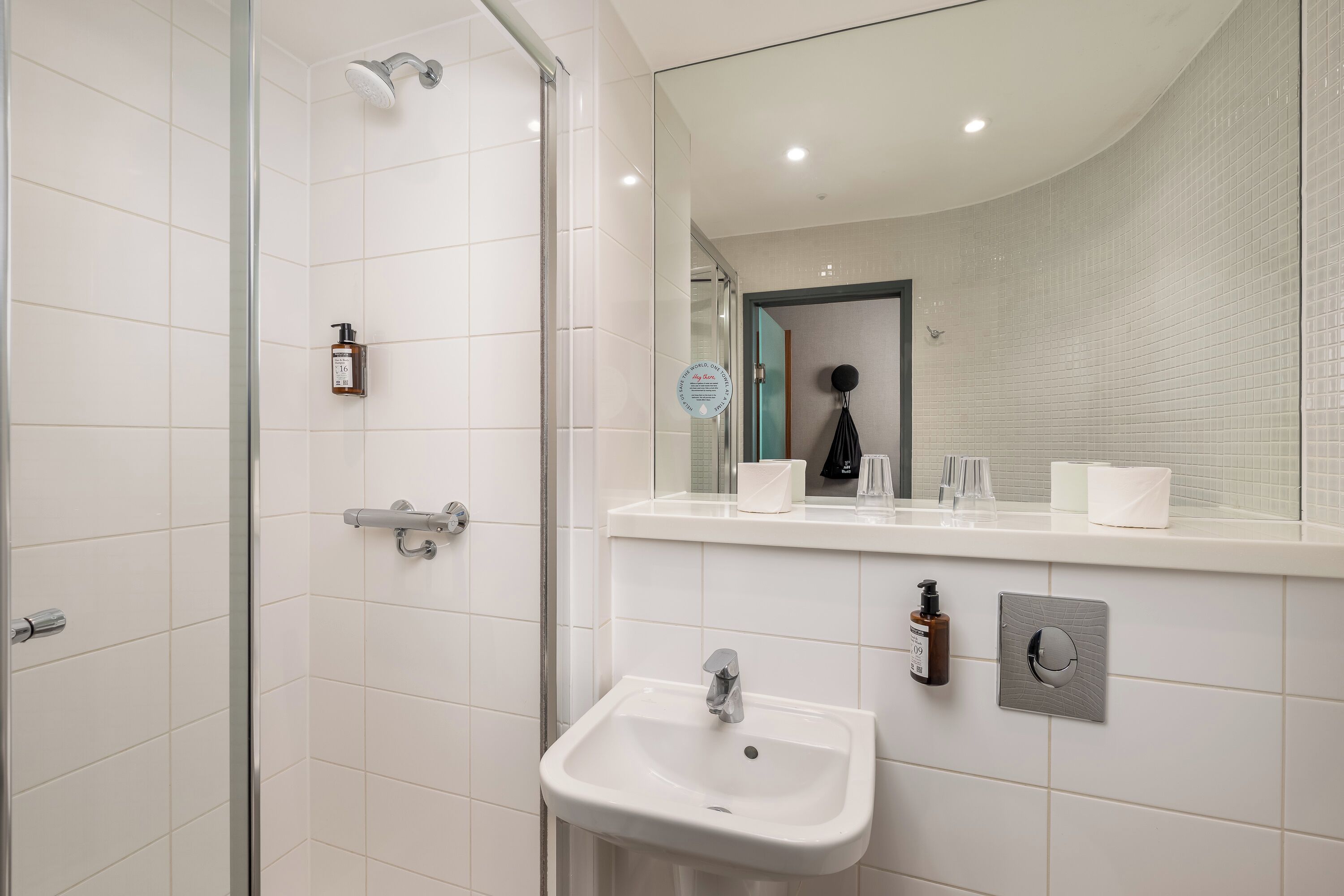A bathroom with a shower, sink, and mirror.