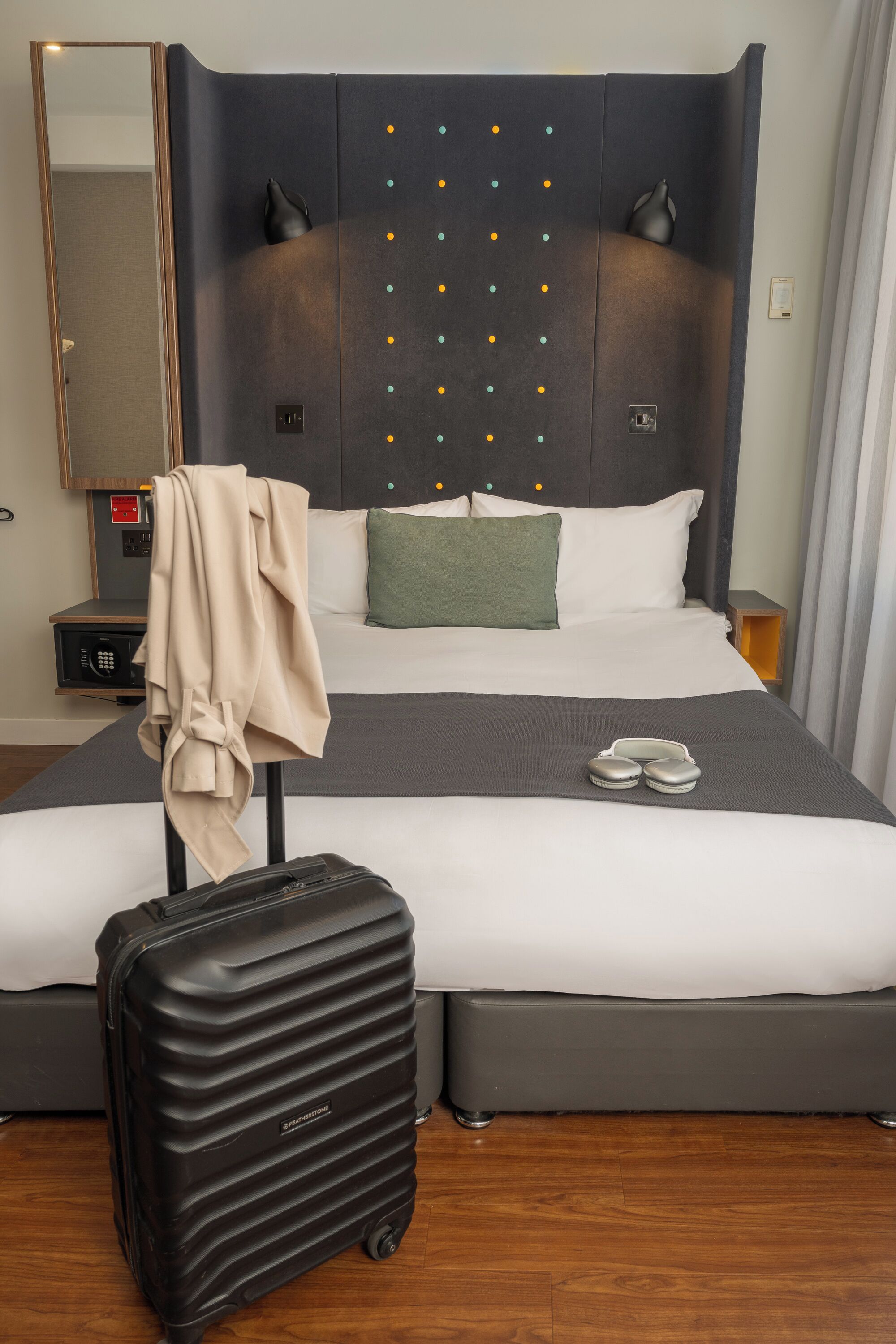 Una habitación de hotel con una cama grande, una maleta y un perchero.