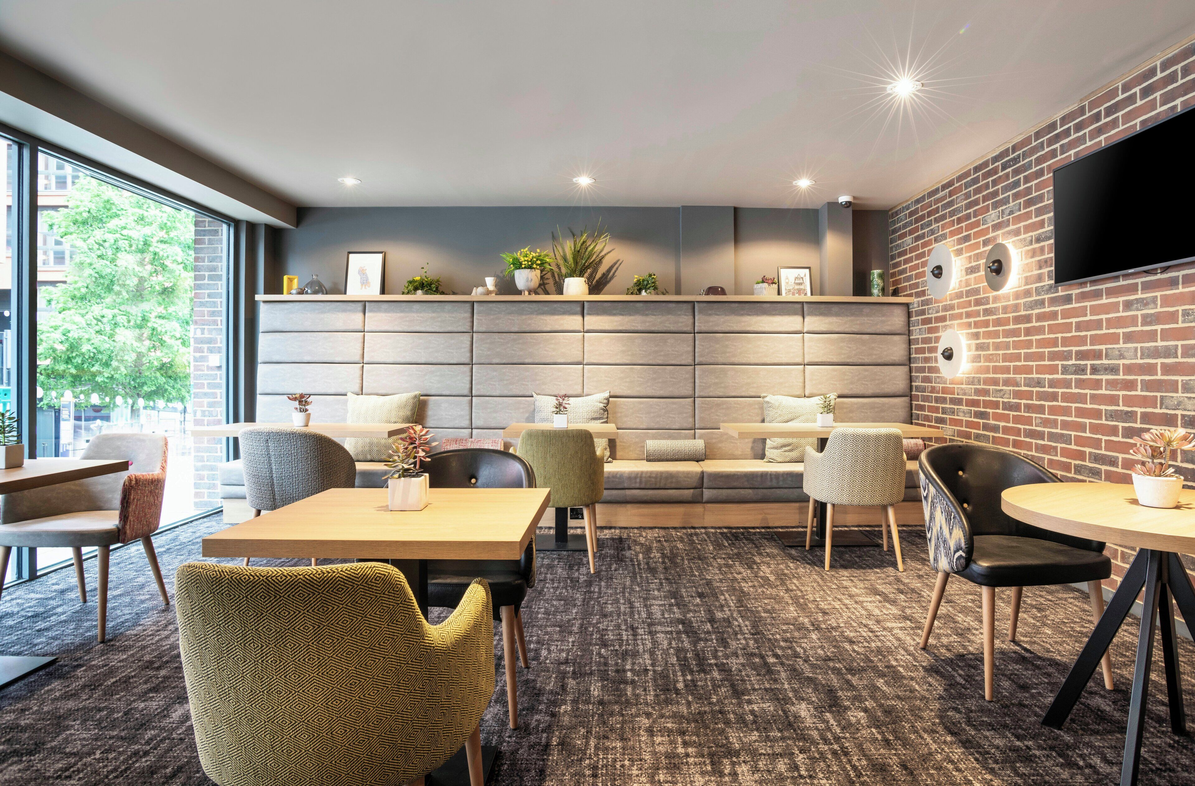 A modern lounge area with a brick wall, a flat-screen TV, and a sofa set.