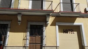 A multi-story hotel with balconies, a closed garage door, and a clear blue sky. - Hotel El Coloso (Jerez de la Frontera)