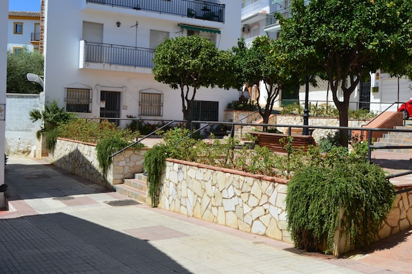 Un edificio residencial de varios pisos con paredes de piedra, balcones y un camino empedrado.