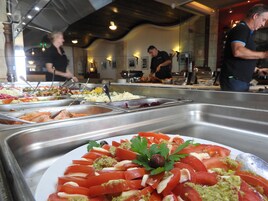 Un bufé con diversas opciones de comida, incluyendo mariscos y ensaladas.
