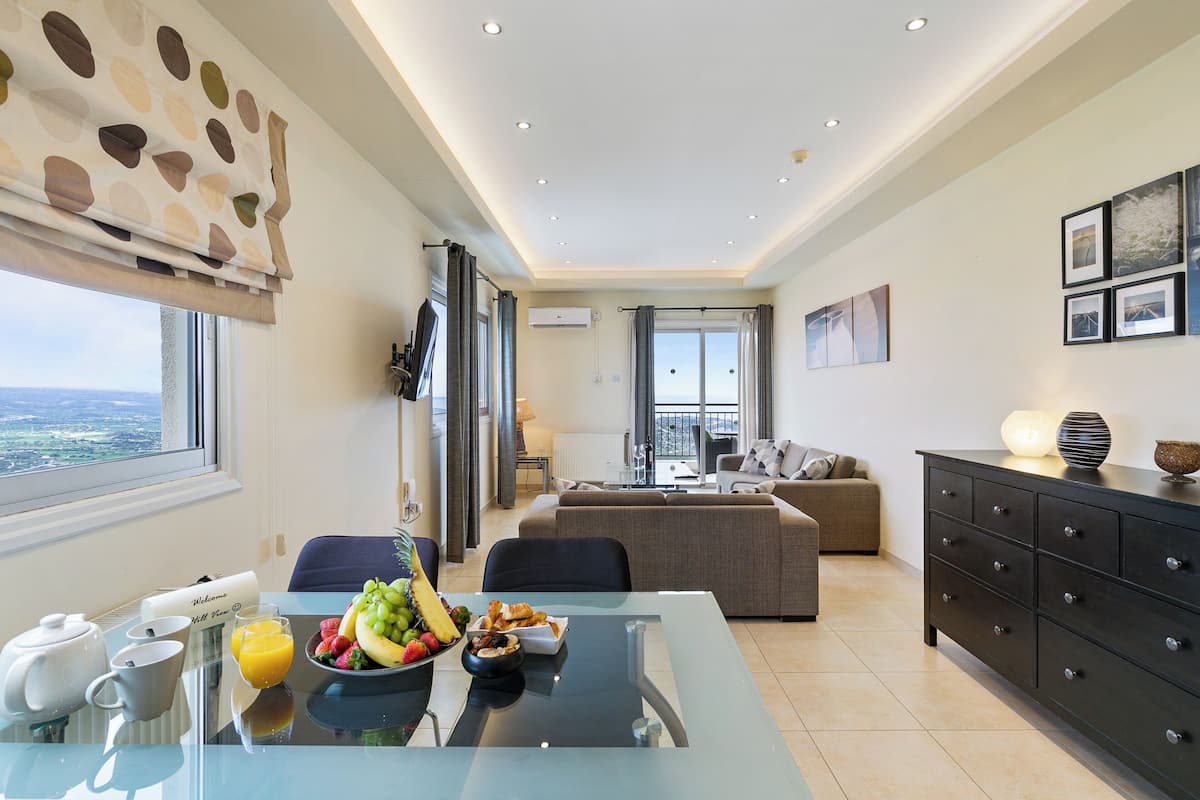 A modern living room with a glass dining table, a sofa, and a black cabinet.
